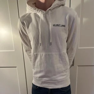 Vit hoodie från Helmut Lang - Säljer en stilren vit hoodie från Helmut Lang med tryck på bröstet. Näst intill helt ny, köpt för 2899 kr från farfetch. Hör gärna av er om frågor!