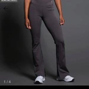  träningsbyxor med slits - Snygga grå/ Beigea träningsbyxor med bootcut-stil och slits vid anklarna samt en liten dragkedja frampå. Byxorna har en tight passform. De är tillverkade i ett mjukt och stretchigt material för maximal komfort. Oanvända. Dom två första bilderna är för att visa hur dom ser ut på det är inte samma färg. Se bild tre för färgen på dom jag säljer 