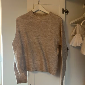 Beige stickad tröja från Uniq Studio str 146/152 - Säljer en mysig beige stickad tröja från Uniq Studio str 146/152. Tröjan har en rund halsringning och långa ärmar med ribbade muddar. Perfekt för kyligare dagar. Hör av dig vid intresse!
