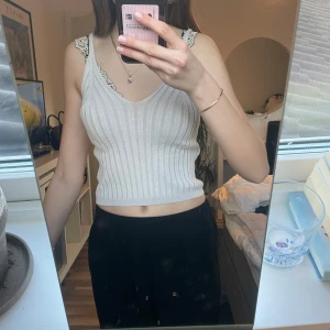 Vit ribbad linnetopp - Säljer en stilren vit ribbad linnetopp med spetsdetaljer vid axelbanden. Toppen har en v-ringad design och är croppad, vilket ger en trendig look. 