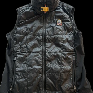 Svart dunväst från Parajumpers - Säljer en stilren svart dunväst från Parajumpers. Västen har en dragkedja framtill och en broderad logotyp på bröstet. Perfekt för lager-på-lager under kyligare dagar, använd cirka 5ggr Org pris: 3499kr