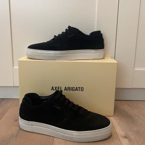 Svarta sneakers från Axel Arigato - Riktigt snygga svarta sneakers från Axel Arigato med vit sula. Skorna har en väldigt stilren design med snörning och är perfekta för en modern look. Skorna är i storlek 42 👟Levereras med originalförpackning, dustbag och stickers! Nypris ligger på 2500kr 💸Skorna är som nya! Skicket 9/10 använda 1 gång endast! Otroligt stilrena och fina väl värt pengarna för ett mega dunder bra pris, bara att höra av dig vid minsta lilla fundering eller fråga ✅