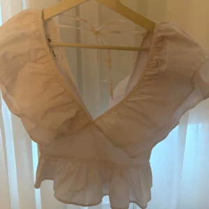 Vit blus med volangdetaljer - Säljer en söt vit blus med volangdetaljer och knytning i ryggen💕 aldrig använd. Storlek M men passar en S mycket bättre! 