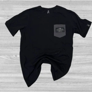Haglöfs T-Shirt - Säljer en svart t-shirt från Haglöfs med en grå bröstficka och logotyp. T-shirten har en rund halsringning och korta ärmar. Perfekt för en avslappnad stil.
