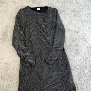 Svart glittrig klänning från Lindex - Snygg svart klänning från Lindex med glittriga detaljer. Klänningen har långa ärmar och en elegant passform. Perfekt för speciella tillfällen när du vill glänsa lite extra. ✨