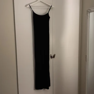 Svart långklänning från Gina Tricot - Snygg svart långklänning från Gina Tricot i storlek XS. Klänningen har smala axelband och en elegant, enkel design som passar perfekt för olika tillfällen. Perfekt för dig som vill ha en stilren look. Använd fåtal gånger.