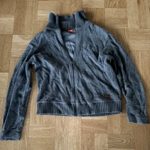 Grå Hugo boss fleecejacka med dragkedja och krage  - Säljer en mysig grå fleecejacka med dragkedja och ribbad krage. Perfekt för kyliga dagar. Jackan har långa ärmar och ribbade muddar vid ärmslut och nederkant.