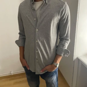 Grå skjorta från Massimo Dutti - Skjorta från Massimo Dutti som passar perfekt till våren. Storlek S, aldrig använd, utmärkt skick. Tveka inte att höra av dig vid frågor eller funderingar.