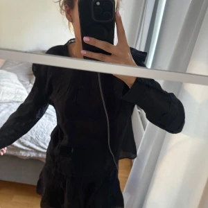 Mango set  - Supersöt svart kort set med långa ärmar och fina spetsdetaljer vid axlar och halsringning. Klänningen har en flowy passform och volang nertill, perfekt för dig som gillar en romantisk och chill vibe.