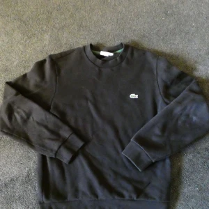 Lacoste,S - Hej, jag säljer en svart Lacoste hoodie som passar med nästan allt. Passformen är jättebra och den är väldigt skön. Om du har fundering så är det bara att skriva😁👍
