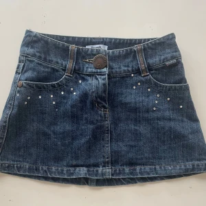 Mörkblå jeanskjol med nitar - Snygg mörkblå jeanskjol med snygga fickor bak. Använd vid ett fåtal gånger säljer då den tyvär e för liten för mig🌸💗