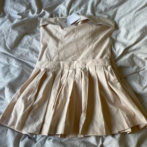 Kortklänning från Zara - Beige/rosa bandou kortklänning från Zara med inbyggda shorts under. Aldrig använd med lappar kvar!