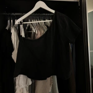 Svart croppad oneshoulder topp - Snygg svart croppad topp med oneshoulder-design och kort ärm. Storlek M!! Ingen användning! Kommer tyvärr ej ihåg vart ifrån för lappen är borta!💗