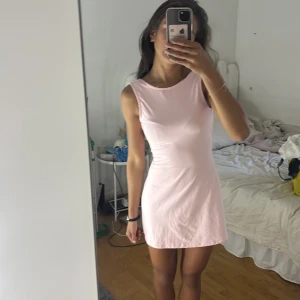 Ljusrosa kort klänning XS - Supersöt ljusrosa kort klänning i stretchigt material. Ärmlös modell med rund hals och öppen rygg som ger en snygg och enkel look. Perfekt för dig som gillar minimalistisk stil och vill ha något bekvämt och stilrent.