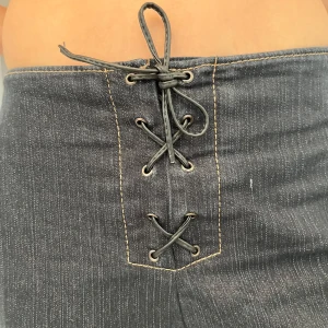 Svarta jeans med snörning i midjan - Snygga svarta jeans med hög midja och unik snörningsdetalj framtill. Jeansen har utsvängda ben och är i mycket bra skick!💞