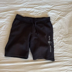 Svarta shorts från Sail Racing S - Svarta shorts från Sail Racing i mjukt material med snörning i midjan och logga längs ena benet. Klassisk loose passform och perfekt längd för chill dagar. Snygg och enkel design som funkar till allt. Storlek S.