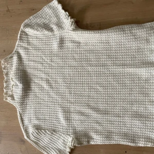 Vit strukturerad topp Forever 21 - Säljer en vit kortärmad topp från Forever 21 med våfflad struktur och volangkant vid ärmslut, hals och nederkant. Toppen har en mjuk och stretchig känsla.