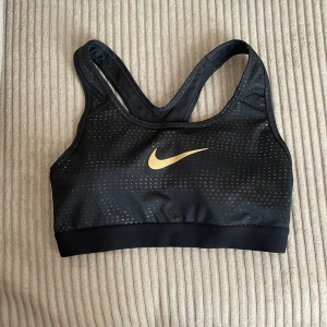 Svart sporttopp Nike Dri-Fit  - Svart sportopp med guldiga prickar från Nike. Lite slitage av mönstret på ryggen se bild. Säljer då den tyvärr är för liten för mig. 