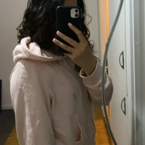 Ljusrosa hoodie med dragkedja - Säljer en kort och skön kofta. Den har en huva, fickor och man kan mör minska luvan med de två snörena framme. Använd fåtal gånger. Man kan styla koftan med flera saker. Min storlek är s men koftan är L och passar perfekt för mig.