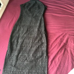 Svart lång spetsklänning - Säljer en svart långklänning med vackert spetsmönster. Klänningen har figurnära passform och är ärmlös, perfekt för dig som vill ha en elegant och stilren look. Materialet är mjukt och följsamt, vilket gör den bekväm att bära hela kvällen.