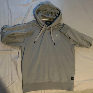 Grå hoodie från Replay med huva - Snygg grå hoodie från Replay med klassisk huva och snörning. Tröjan har lång ärm, ribbade muddar och en liten broderad logga på bröstet. Perfekt för en chill och stilren look. Materialet är mjukt och skönt, troligtvis bomullsmix.