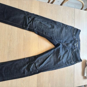 Mörkblå Tiger of Sweden jeans - Snygga mörkblå jeans från Tiger of Sweden med klassisk femficksdesign och kontrastsömmar. Jeansen har rak passform och är tillverkade i slitstarkt bomullsjeans. Perfekta för dig som gillar stilrena och tidlösa byxor. Kom privat för mer info 