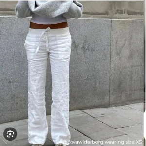 Vita linnebyxor från alobha label  - Snygga vita linnebyxor med knyt i midjan och avslappnad passform. Byxorna har raka ben och är perfekta för en chill och stilren look. Lätta och luftiga, passar grymt till sneakers eller sandaler.