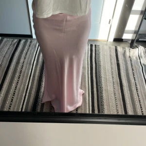 Ljusrosa långkjol i satin - Supersnygg ljusrosa långkjol i satin med slimmad passform. Kjolen har en mjuk glansig yta och faller snyggt längs kroppen. Jag är ca 160 cm och då går kjolen ner till fötterna.  Kjolen är från Vera Moda, st XS 🩷