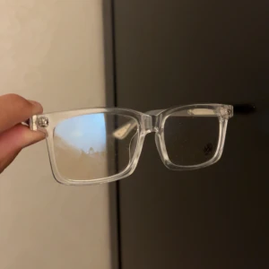 Klara glasögon Chrome Hearts - Säljer ett par rektangulära glasögon från Chrome Hearts med transparent båge och silvriga detaljer på skalmarna. Snygg logga och blommönster på glaset ger en unik vibe. Perfekta om du vill sticka ut med stilrena men ändå coola brillor.