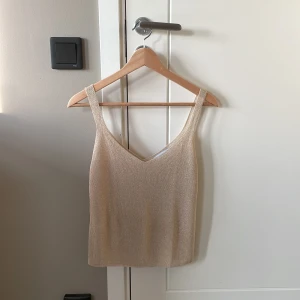 Glittrig champagnefärgad linnetopp MNG - Champagnefärgad linnetopp från mango med glittrig finish. Toppen har smala axelband, v-ringning och är croppad i modellen. Perfekt för dig som vill sticka ut med en stilren men ändå festlig look. Toppen är i st S och aldrig använd. 💛