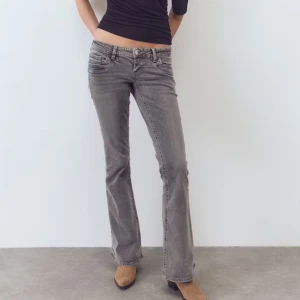 Grå bootcut jeans låg midja - Säljer ett par grå jeans med bootcut-modell och låg midja från Gina 14+. Jeansen har klassisk femficksdesign, bälteshällor och är tillverkade i mjukt bomullsmaterial med lite stretch. Perfekta för dig som gillar en avslappnad men ändå snygg look.