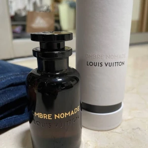 Louis Vuitton Ombre Nomade parfym - Exklusiv parfym från Louis Vuitton, Ombre Nomade. Flaskan är svart med guldtext och har en lyxig, rundad form. Kommer i en elegant vit förpackning med svart detalj. Perfekt för dig som gillar unika och djupa dofter.