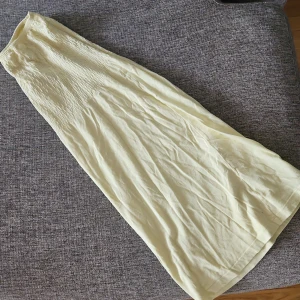 Ljusgul tubklänning med smock.  - Tubklänning i ljusgul färg med smock upptill och rak, luftig passform. Klänningen är ärmlös och har en enkel, stilren design som passar perfekt till varma dagar. Tillverkad i mjukt bomullstyg för en bekväm känsla. Klänningen har en fläck som inte går bort, men syns knappt.