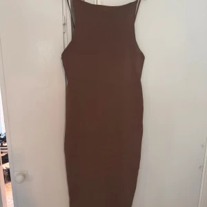 Brun ribbad långklänning med smala axelband - Säljer en brun långklänning med smala axelband och ribbad struktur. Klänningen har en tight passform och är ärmlös, perfekt för dig som gillar en enkel men stilren look. Materialet är mjukt och stretchigt, vilket gör den bekväm att bära hela dagen.