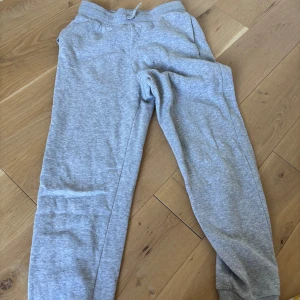 Grå mjukisbyxor med resår - Säljer ett par klassiska grå mjukisbyxor med resår i midjan och muddar vid bensluten. Perfekta för chill dagar eller när du vill vara extra bekväm. Tillverkade i mjukt bomullsmaterial som känns skönt mot huden.