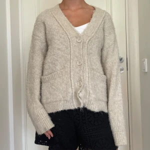 Beige stickad kofta från Zara - Mysig beige stickad kofta från Zara med v-ringning, stora knappar och två fickor framtill. Koftan har en loose passform och långa ärmar, perfekt att slänga på sig när det är kyligt. Enkel och stilren design som funkar till det mesta. Skriv om du undrar något, kolla min profil innan du trycker på köp nu💕💕