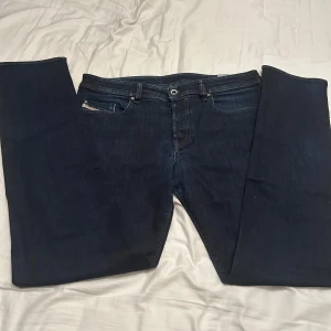 Diesel Buster mörkblå jeans - Mörkblå jeans från Diesel, modell Buster. Klassisk femficksdesign med raka ben och diskreta slitningar. Jeansen har normal passform och är tillverkade i mjukt denimtyg som sitter skönt hela dagen.