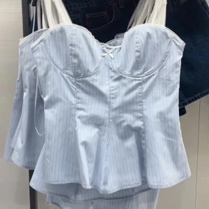 Blåvit randig korsett-topp med rosett - Supersöt korsett-topp i ljusblått och vitt med tunna ränder, formade kupor och liten rosett framtill. Toppens material är bomull och den har smala axelband samt en lätt utsvängd nederdel för en feminin siluett. Perfekt för en trendig och söt look.