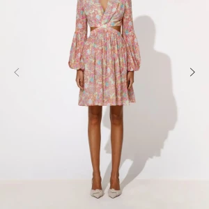 SÖKER ej säljer ! By Malina klänning som på bild - By Malina kortklänning med blommigt mönster i rosa, blått och vitt. Djup v-ringning, cut-out i midjan och ballongärmar.