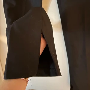 Svarta kostymbyxor med slits - Svarta kostymbyxor med raka ben och slits nertill vid bensluten. Är ca 1 dm för långa för mig som är 168