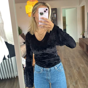 Svart sammetsblus med utsvängda ärmar - Svart sammetsblus med v-ringning och långa utsvängda ärmar. 