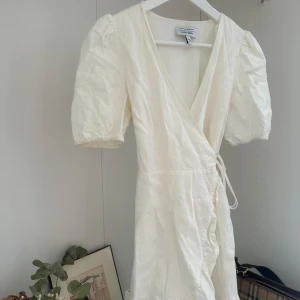 Vit omlottklänning från & Other Stories - Superfin vit omlottklänning från & Other Stories med puffärmar och knyt i midjan. Klänningen har v-ringning och är tillverkad i ett linnematerial. Inga tecken på användning.