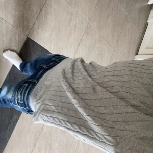 Ljusgrå kabelstickad tröja från Gant - Säljer en ljusgrå kabelstickad tröja från Gant i bomull. Tröjan har rund halsringning, ribbade muddar och Gant-logga broderad på bröstet. Perfekt för dig som gillar klassisk och clean stil.