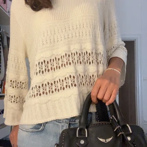 Vit stickad tröja med hålmönster från Mango - Superfin vit stickad tröja med hålmönster och breda ribbade kanter. Tröjan har en avslappnad passform och långa ärmar, perfekt att styla med jeans för en chill look.