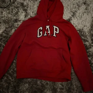 Röd GAP hoodie - Säljer min oanvända GAP hoodie då den helt enkelt inte kom till användning. Strl XS och röd.
