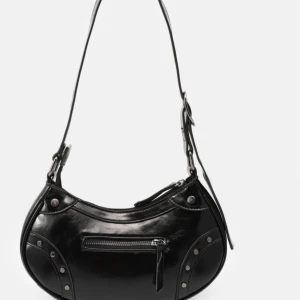 Svart axelväska i skinn med nitar - Cool svart axelväska i skinn med rundad form och justerbart axelband. Väskan har silvriga nitar och detaljer samt en dragkedja framtill för extra edge. Perfekt för dig som gillar en stilren men ändå tuff look.