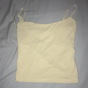 Beige linnetopp från Gina Tricot XS - Säljer en stilren beige linnetopp från Gina Tricot, basically basics-kollektionen. Toppen har smala axelband och ärmlös design, perfekt för varma dagar eller lager-på-lager. Enkel och clean look som funkar till allt.