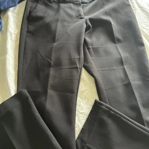 Svarta vera lågmidjade kostymbyxor från bikbok - Säljer ett par svarta kostymbyxor med klassisk passform och lågmidjade i modellen vera och längden petite, jag har spretat sömen längst ner samt lite tunning av tyget vid ett knä men inget som man ser så tydligt🥰 