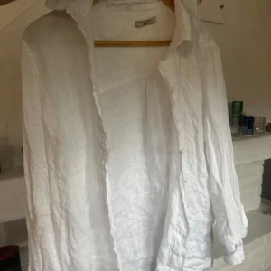 Vit linneskjorta med knappar - Säljer en luftig och stilren vit skjorta i linne från Gina tricot. Skjortan har långa ärmar, klassisk krage och knäppning framtill.