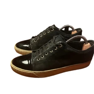 Svarta sneakers med lackdetaljer - Snygga svarta sneakers med coola lackdetaljer på tån och klassisk snörning. Ovandelen är i mocka och sulan är i kontrasterande brun färg. Perfekta för dig som vill ha en stilren men ändå unik look.